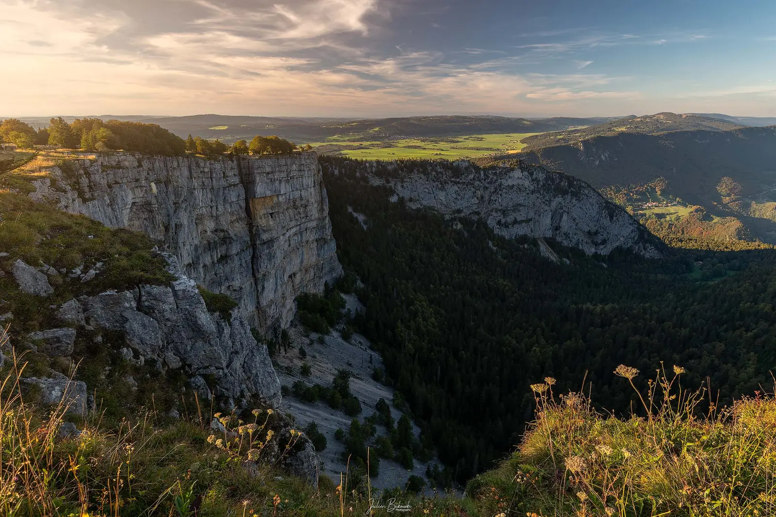 Début septembre, 19 h : la paroi vue de profil, verticale, et la vallée habitée qui s'ouvre en contrebas.